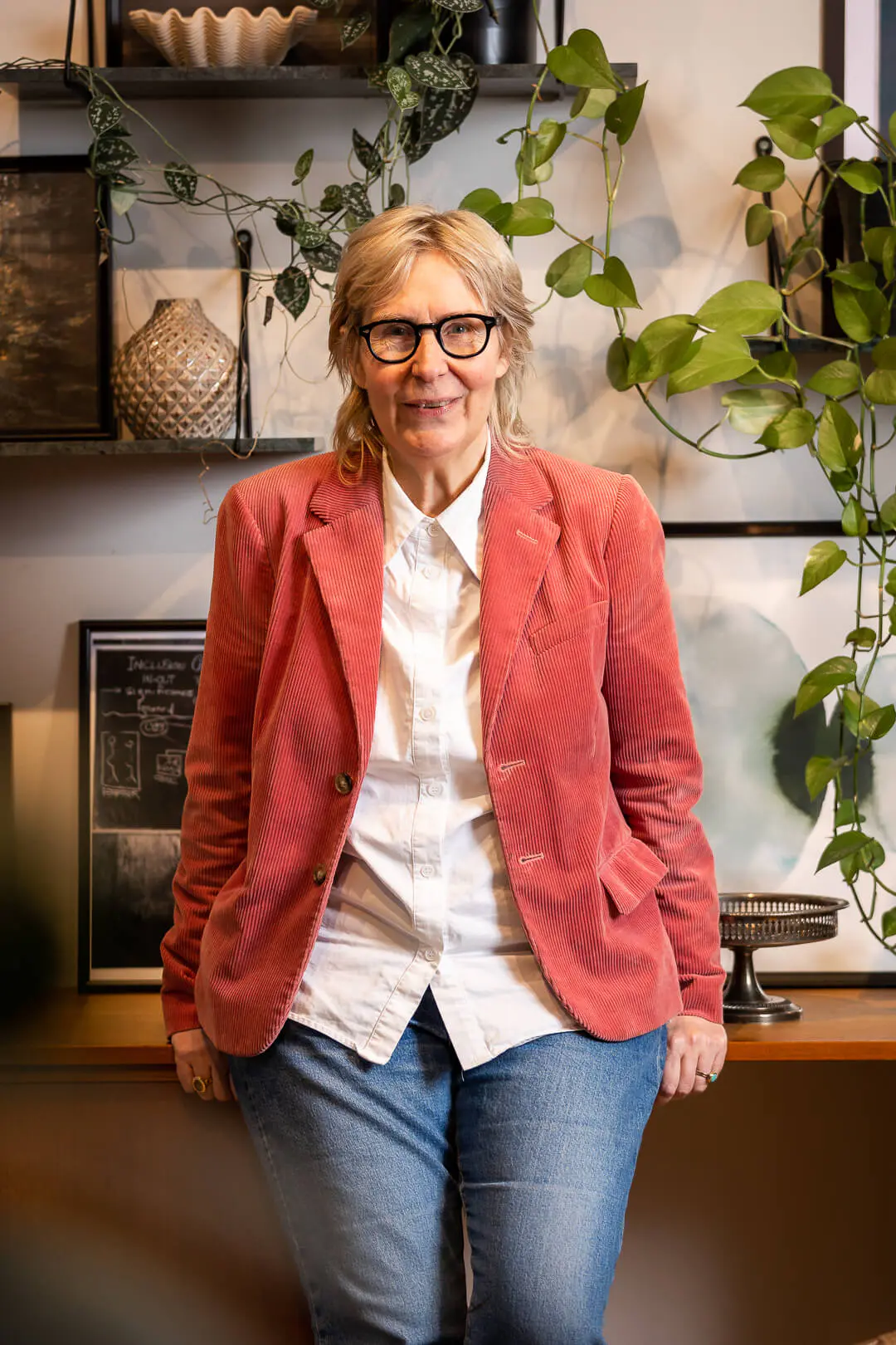 Karin Tenelius in a red jacket, standing in a plant-filled room